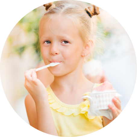 A young girl enjoying a scoop of ice cream, looking content while holding a spoon and a small bowl.