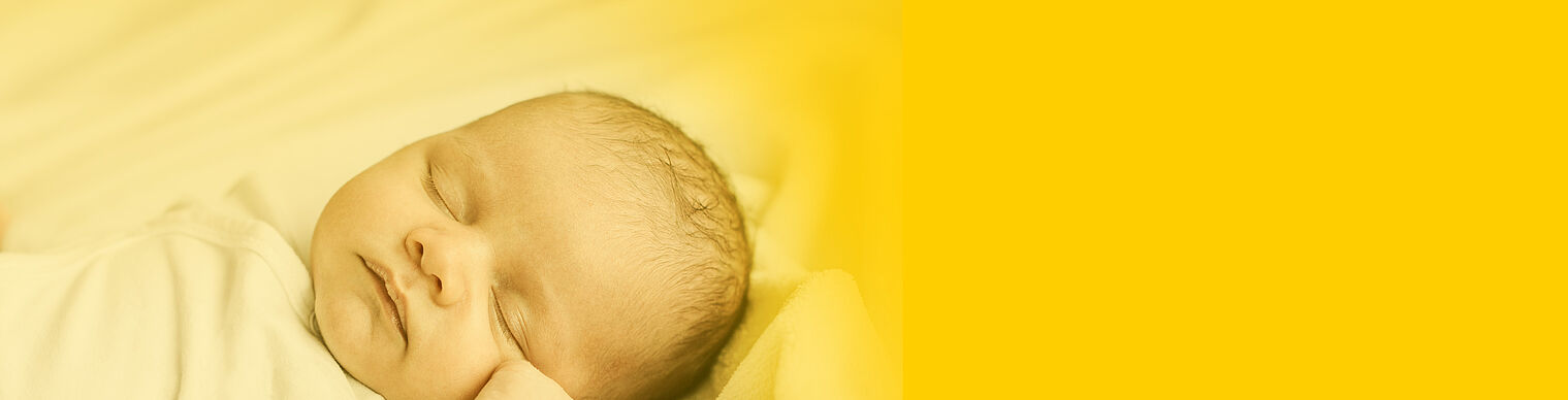 Newborn baby sleeping peacefully on a soft yellow blanket